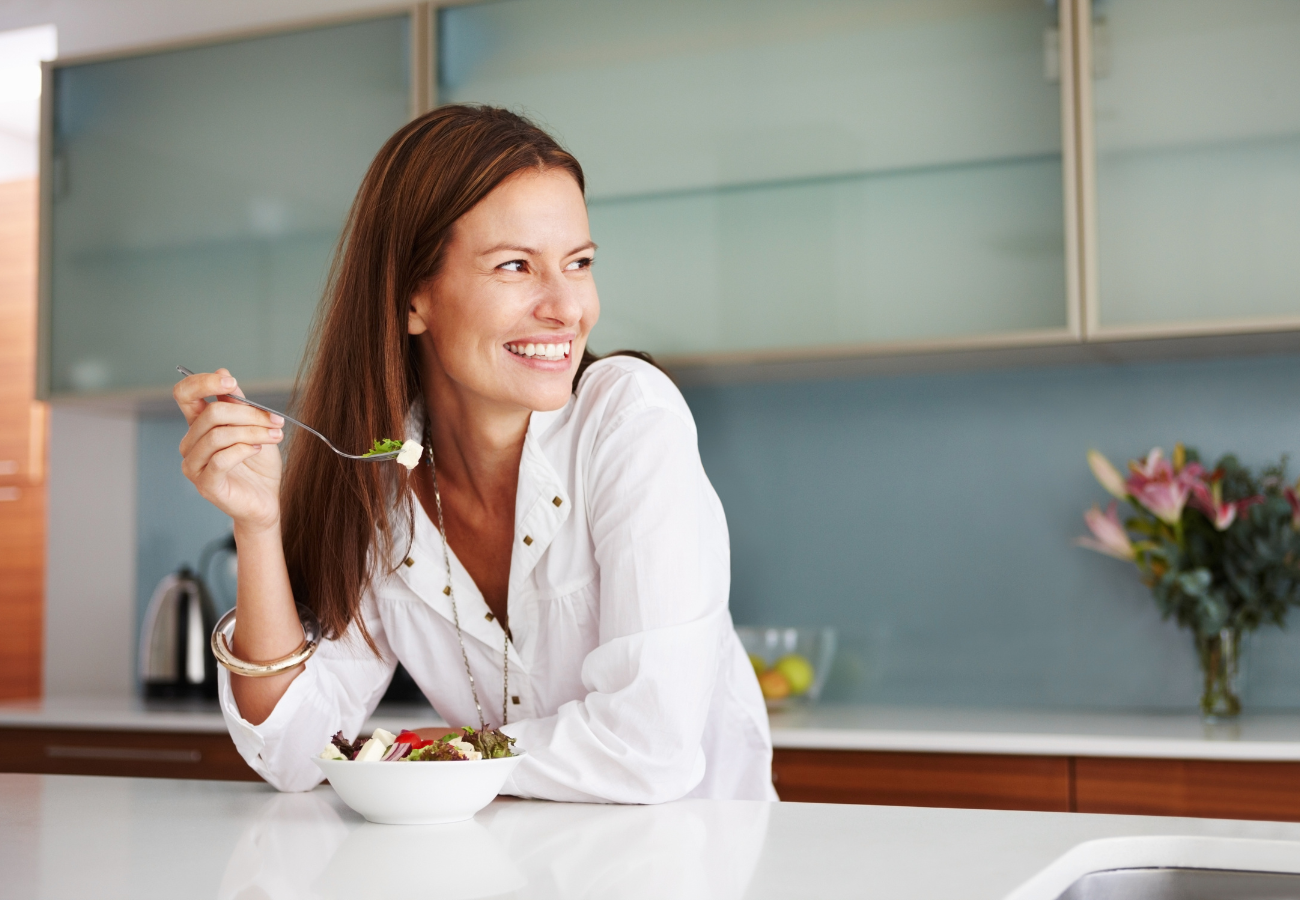 Image of a woman eating a salad and smiling on Eldorado Hair Replacement's website
