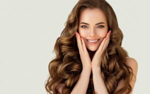 Brunette woman smiling and holding her face.