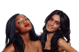 Two women with dark hair standing close together and smiling.