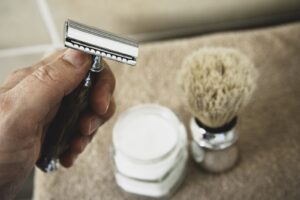 A hand holding a razor above shaving materials