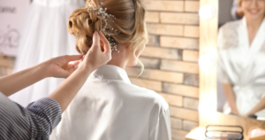 A hairstylist styling an updo on a blonde woman