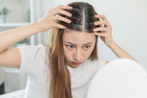 Image of a woman examining her part for hair loss.