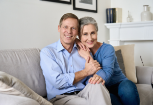 Image of an older couple smiling and sitting together on a couch