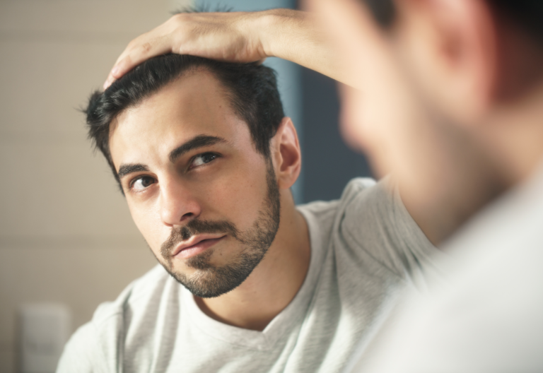 Image of a man looking at his hairline in the mirror