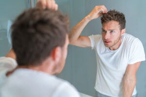 Image of a man looking at his hair in the mirror