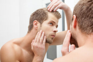A man looking at his hair in the mirror