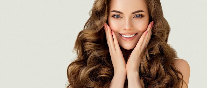 Brunette woman smiling and holding her face.